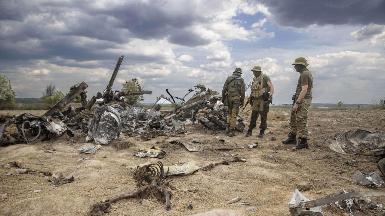 Ukrainian soldiers walk among the wreckage of a Russian military helicopter. Photo: Gary Ramage