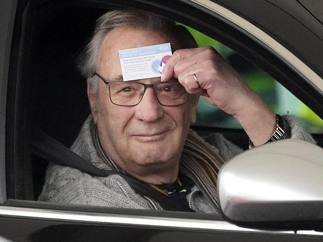 A man shows off his immunisation record card at a drive-thru COVID-19 vaccination centre at Hyde Leisure Centre in England. Picture: Christopher Furlong/Getty