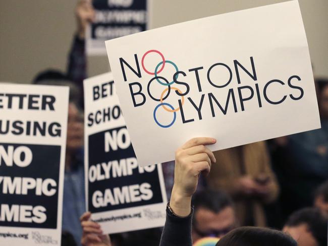 FILE - In this Feb. 5, 2015, file photo, people hold up placards against the Olympic Games coming to Boston, during the first public forum regarding the city's 2024 Olympic bid, in Boston. Boston's mayor delivered a harsh blow to the city's effort to host the 2024 Olympics on Monday, July 27, 2015, when he declared he wouldn't sign any document "that puts one dollar of taxpayer money on the line for one penny of overruns on the Olympics." That document is the host city contract that most in the Olympics consider crucial to any city's success. (AP Photo/Charles Krupa, File)