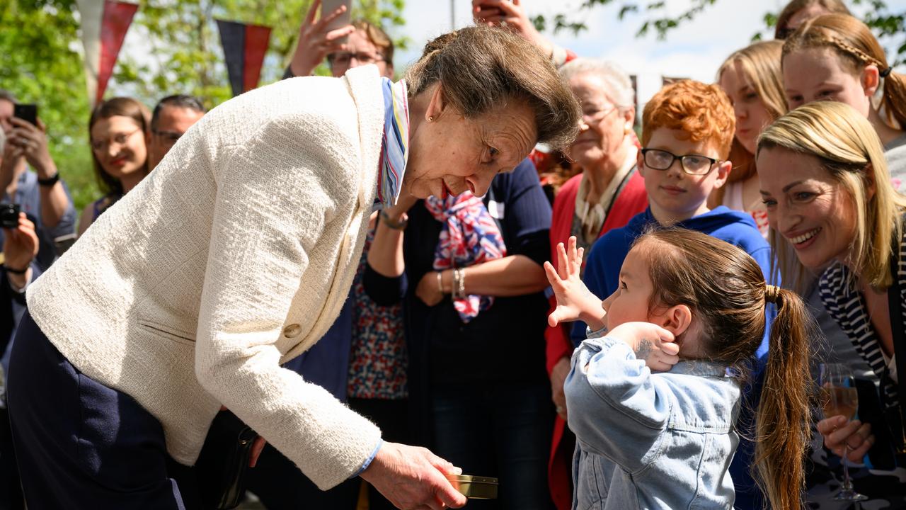 Princess Anne presents a young girl with a commemorative tin of old coins as she visits a Coronation street party. Picture: Getty Images