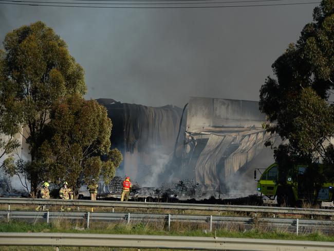 Fire crews mop up after battling a huge factory fire in Derrimut. Picture: Andrew Henshaw