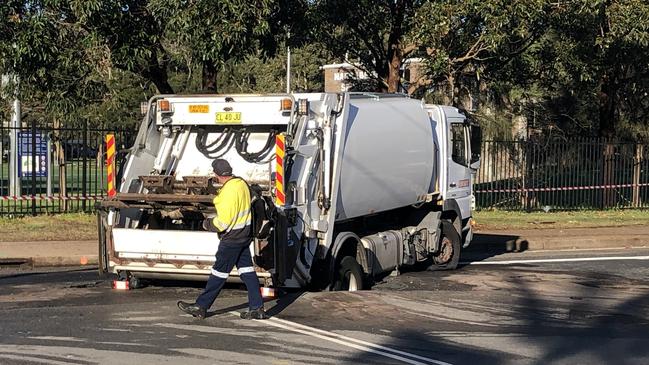 The driver of the garbage truck that has fallen into a sinkhole in Namona St, Narrabeen, inspects the vehicle. Picture: Jim O'Rourke.