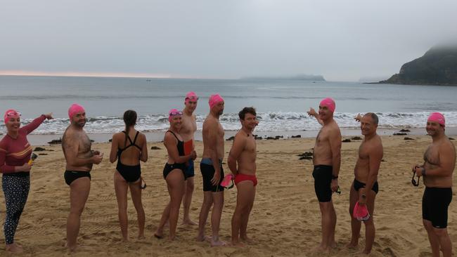 It’s out there somewhere. Swimmers point to their goal of Lion Island covered in fog. Picture: Richard Noone