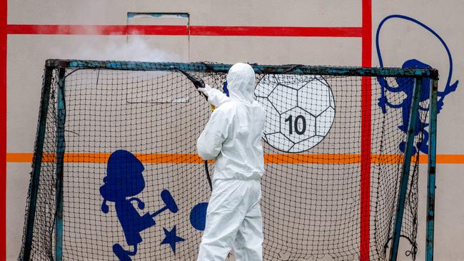 A worker cleans surfaces at Kensington Primary School after two parents contracted the virus. Picture: Jake Nowakowski