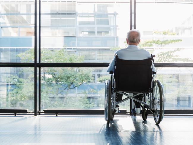 Senior Man in Wheelchair looking out of a window in a hospital corridor. Elder abuse. Picture: iStock