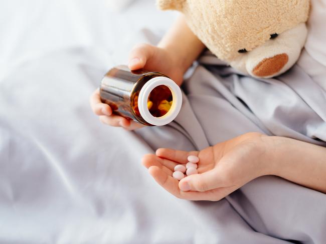 Child taking medicines pills. Sick eight years boy lying in bed patient boy illness drugs istock