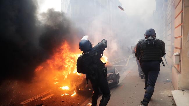 TOPSHOT - A riot police throws tear gas during a protest of "yellow vests" (gilets jaunes) against rising costs of living on December 8, 2018 in Paris. - Paris was on high alert on December 8 with major security measures in place ahead of fresh "yellow vest" protests which authorities fear could turn violent for a second weekend in a row. (Photo by Thomas SAMSON / AFP)