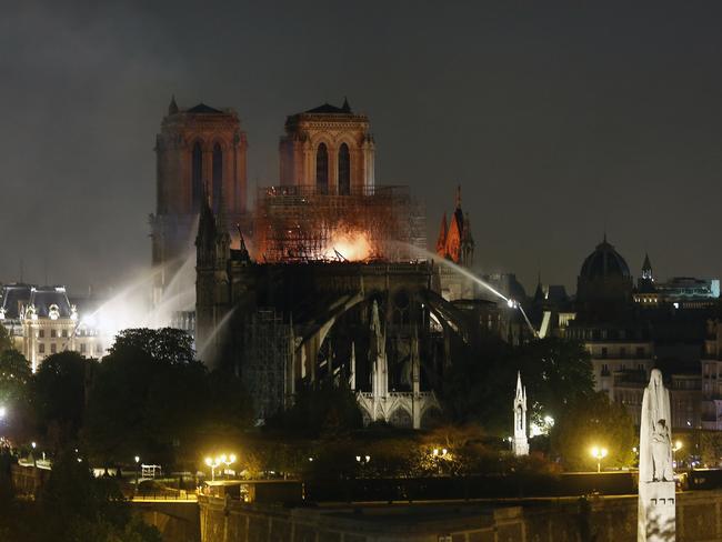 Firefighters tackle the blaze as flames and smoke rise from Notre Dame cathedral as it burns in Paris, Monday, April 15, 2019. Massive plumes of yellow brown smoke is filling the air above Notre Dame Cathedral and ash is falling on tourists and others around the island that marks the center of Paris. (AP Photo/Thibault Camus)