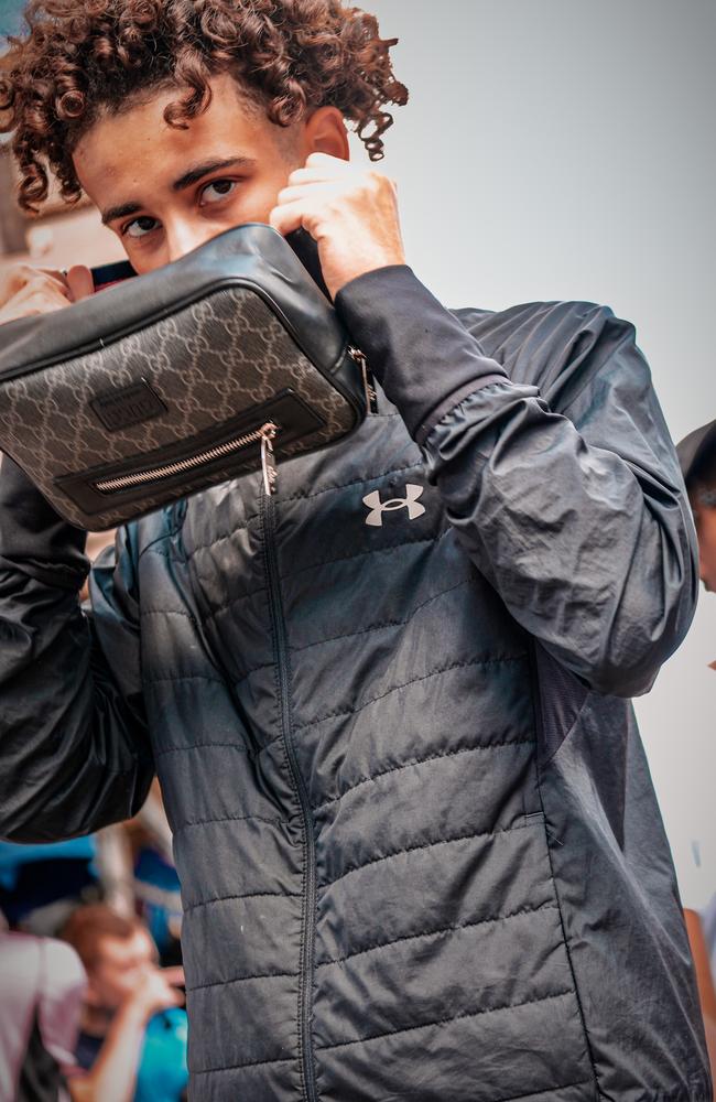 A young man tries on a replica of the $2000 Gucci stripe canvas belt bag that Lyst.com says has surged 756 per cent in month-on-month searches. Picture: James Weir/news.com.au