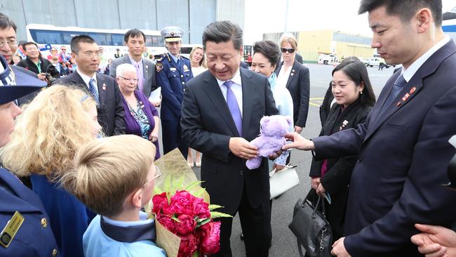 Chinese President Xi Jinping is given a gift of Bobbie the bear by two students on his arrival in Hobart.