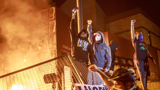 Protesters make the ‘black power’ salute as flames rise from the Third Police Precint. Picture: AFP