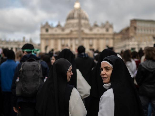 Nuns look on as they queue to enter the Vatican, with St Peter's Basilica in the background. Picture: AFP