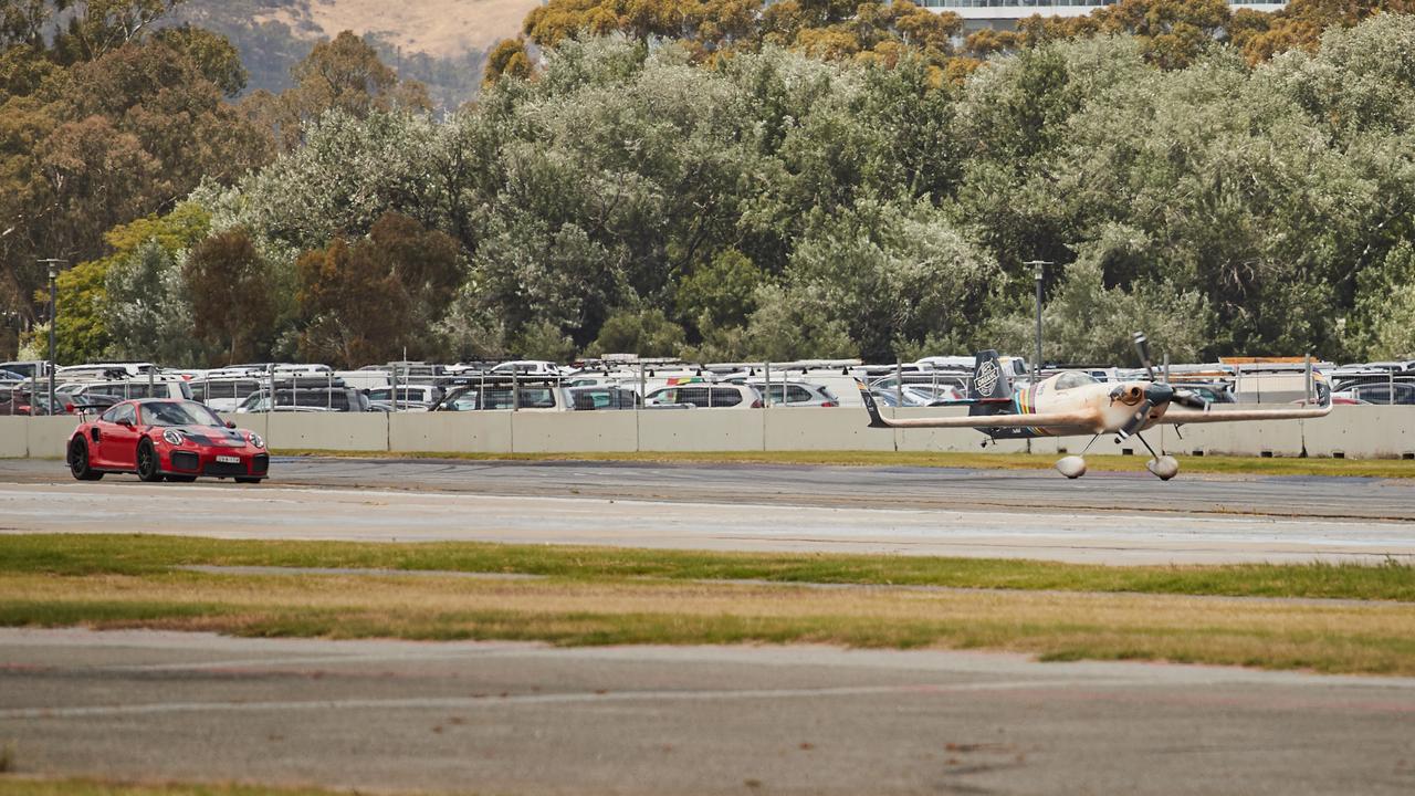 The Red Bull Air Race plane leaves behind Jim Richards in the Porsche GT2RS. Picture: Matt Loxton