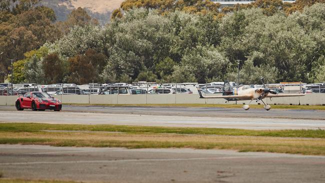 The Red Bull Air Race plane leaves behind Jim Richards in the Porsche GT2RS. Picture: Matt Loxton