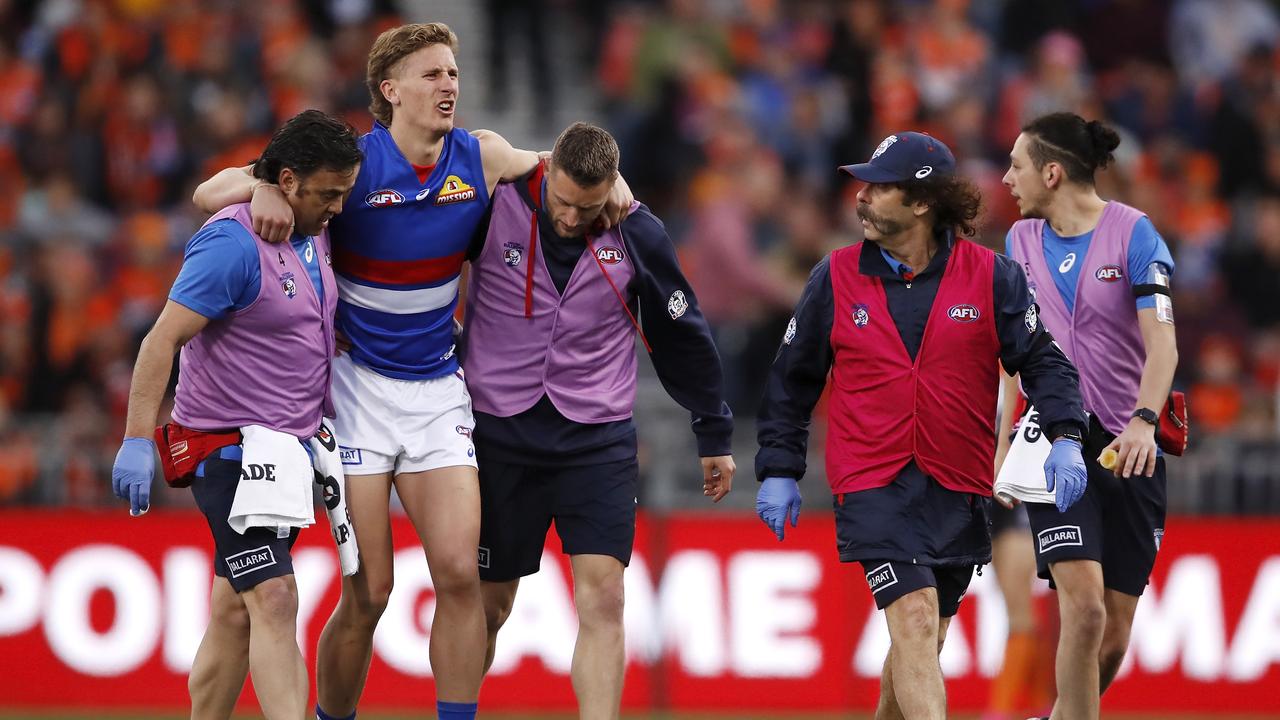 Aaron Naughton is helped from the ground after landing awkwardly in a marking contest on Saturday. Picture: Dylan Burns.