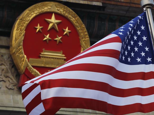 FILE - In this Nov. 9, 2017 file photo, an American flag is flown next to the Chinese national emblem during a welcome ceremony for visiting U.S. President Donald Trump outside the Great Hall of the People in Beijing. China warned Washington on Thursday, Jan. 10, 2018,  it will "resolutely safeguard" its interests ahead of a possible decision in an investigation into whether Beijing improperly pressures foreign companies to hand over technology. (AP Photo/Andy Wong, File)