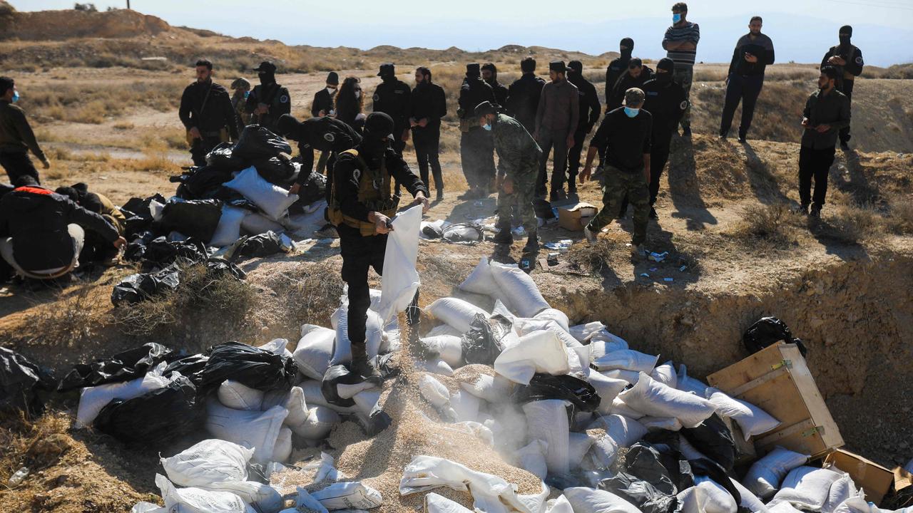 Members of the security forces of Syria's new authorities unload sacks of the drug Captagon to a field to burn them near the Fourth Division's Security Bureau. (Photo by Bakr ALKASEM / AFP)