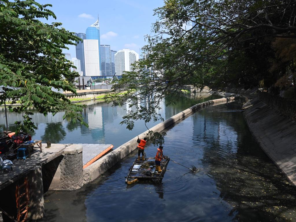 Workers cleaning up a flood mitigation pond. Picture: Goh Chai Hin/AFP