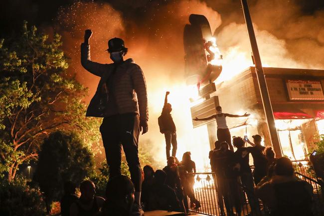 Protestors demonstrate outside of a burning fast food restauran in Minneapolis. Picture: AP