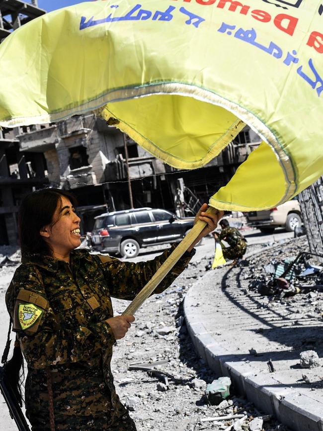 Rojda Felat, a Syrian Democratic Forces (SDF) commander, waves her group's flag at the iconic Al-Naim square in Raqqa. Picture: AFP