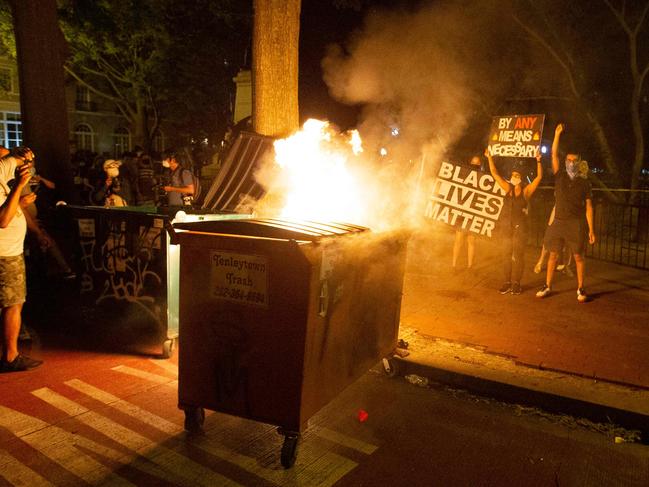 Demonstrators hold up banners next to a burning dumpster outside of the White House. Picture: AFP