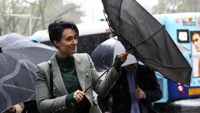 Sarah Budge’s usual steely demeanour turned to a laugh when her umbrella flew up as she arrived at her Sydney gun possession trial. Picture: AAP