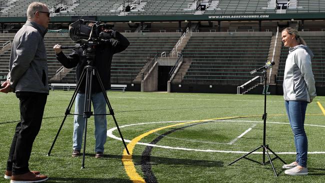 Chief Sports Photographer Jim Forner (C) films as WBAL Sports Anchor/Reporter Pete Gilbert (L) interviews Loyola womens lacrosse coach Jen Adams (R) about the loss of their season due to the COVID-19 pandemic. Picture: Patrick Smith/Getty Images/AFP