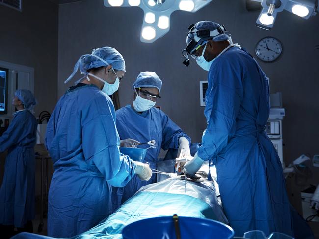 ****Must credit: iStock****.Shot of a team of surgeons performing a surgery in an operating room. Medical Supplies, Emergency Services, Science and Technology, Women, Men, Group Of People, Part Of A Series, Surgical Equipment, Protective Glove, Medical Procedure, Female Doctor, Surgical Cap, Emergency Room, Protective Mask - Workwear, Surgical Mask, Standing, Working, Moving Activity, Expertise, Cooperation, Teamwork, Concentration, Healthcare And Medicine, Science, Selective Focus, Horizontal, Color Manipulation, Scientist, Surgeon, Doctor, Nurse, Medical Occupation, Healthcare Worker, Professional Occupation, Occupation, Patient, People, Reflection, Operating Room, Hospital, Medicine, Intensive Care Unit, Medical Equipment, Computer Monitor, Equipment, Surgery, Eyewear, Protective Workwear, Specific Clothing, Male Doctor, Team, Colleague