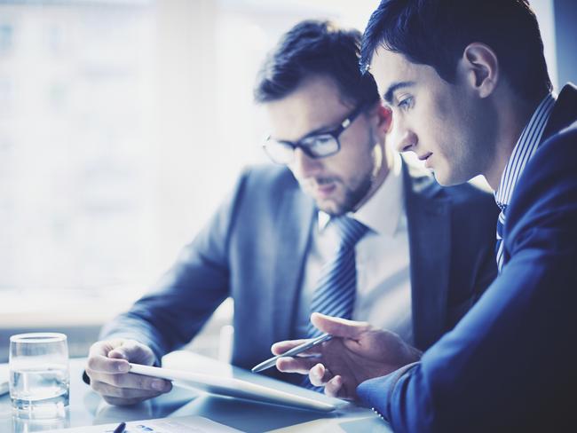 Image of young businessman pointing at touchpad while explaining his idea to colleague at meeting