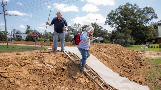 John and Julie Quinlan, who live on the wrong side of the Echuca wall, cross it with supplies. Picture: Jason Edwards