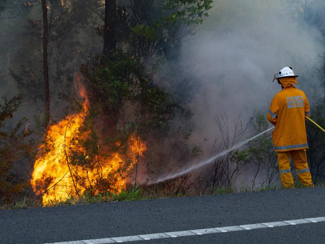 Rural firefighters work to control a blaze near the Sunshine Coast motorway that threatened a number of homes near Peregian Springs and forced residents to evacuate near Lake Weyba.  Photo Lachie Millard