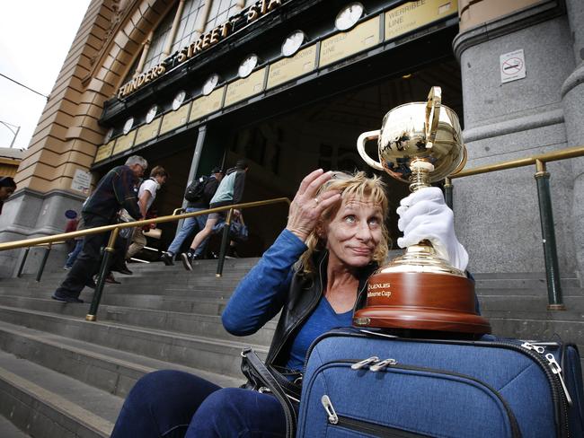 Jane Sullivan from New Zealand checks her hair in the reflection of the Cup while waiting on the steps of Flinders Street Station for her daughter. Picture: David Caird