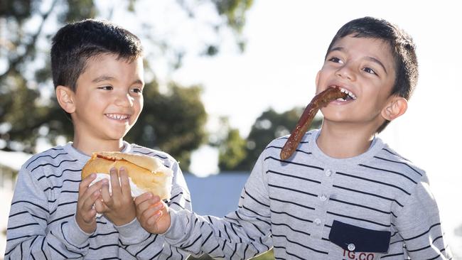 Sam Haddad 5 and Hayden Haddad 5, have fun with their sausage sizzles at Condell Park Public School. Picture: Matthew Vasilescu