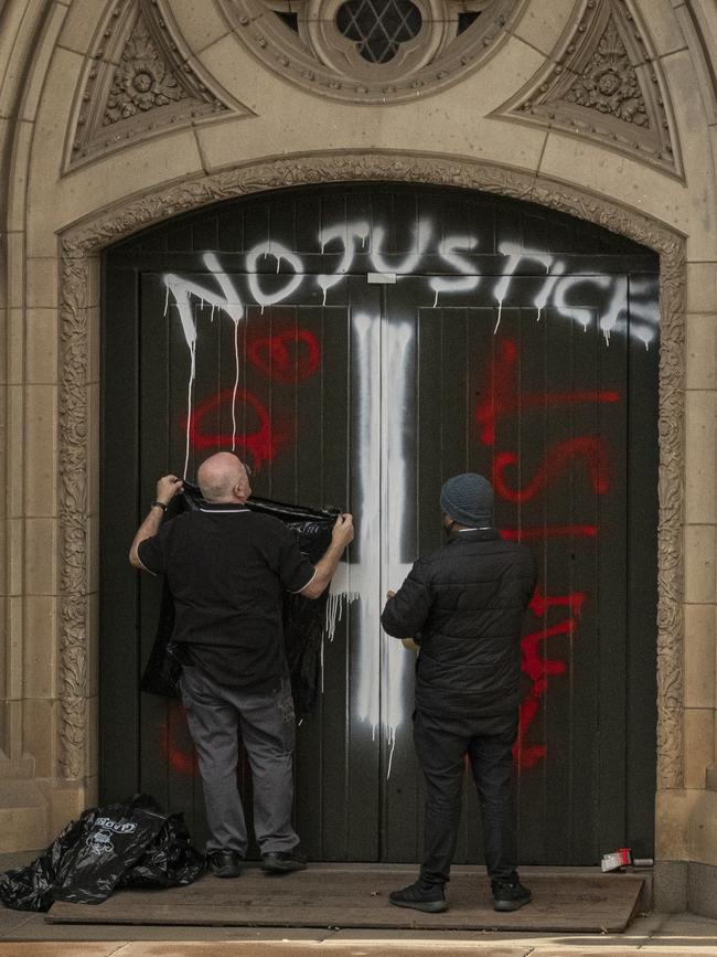 Workers cover graffiti at St Patrick’s Cathedral after the High Court ruling. Picture: AAP