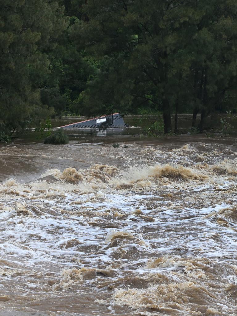 Floodwaters in the Coomera River spill over the Oxenford Weir. Picture: Glenn Hampson