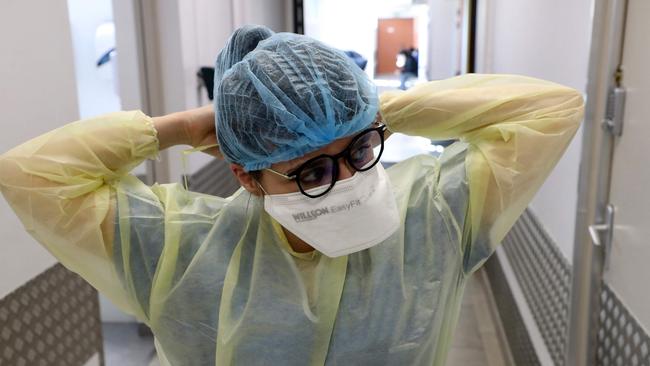 A nurse adjusts her face protections before taking care of patients. Photo: AFP