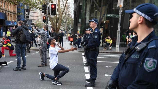 A protested takes a knee in front of police officers in Sydney. Picture: AAP/Dean Lewins