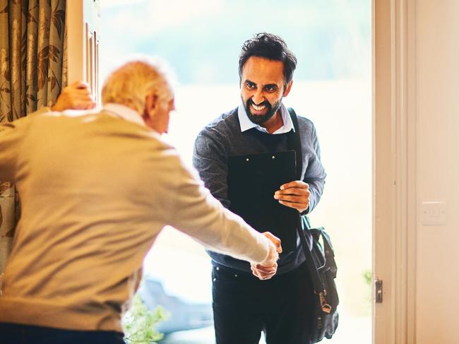 Young male community healthcare worker being welcomed by a senior man at his home; Aged care home care visit, senior generic