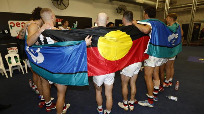 St Kilda players wrap themselves in the Aboriginal and Torres Strait Islander flags to sing the song after winning in Sir Doug Nicholls Round. Picture: Darrian Traynor/AFL Photos/Getty Images