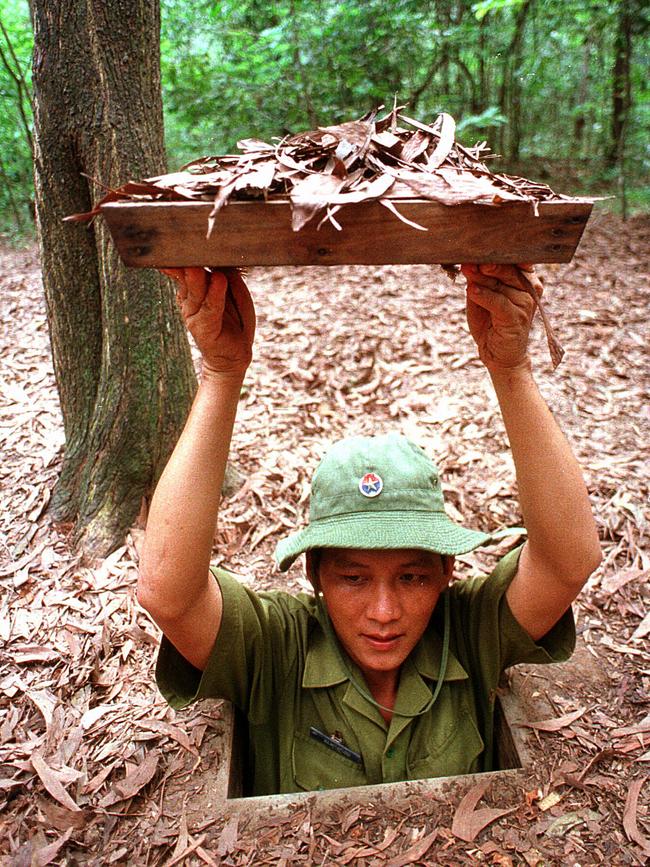 A man shows a trapdoor entrance to Cu Chi tunnels that were used by the Vietcong during the Vietnam War.