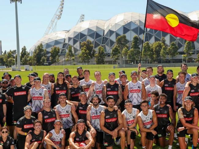 Collingwood players pose with the Aboriginal flag