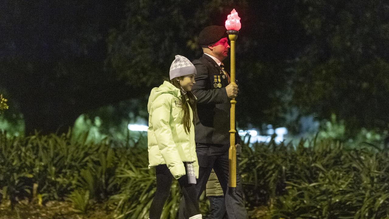 The Torch is carried along Margaret St in the pre-dawn by Joshua Hawkins with daughter Arianna Riwoe on the march to the Anzac Day Toowoomba Dawn Service, Tuesday, April 25, 2023. Picture: Kevin Farmer