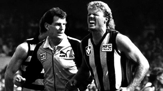 Dermott Brereton is helped from the field after being cleaned up in the 1989 Grand Final.