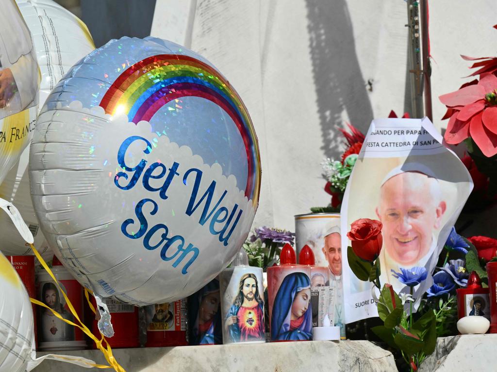 Balloons are attached at the statue of John Paul II where people come to pray outside the Gemelli hospital where Pope Francis is hospitalised. Picture: AFP