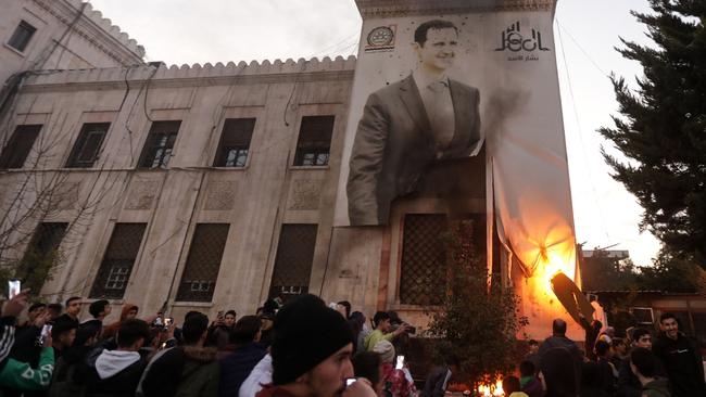 Hama resident set ablaze a large banner bearing a picture of Syrian President Bashar al-Assad hanging on the facade of a council building on Thursday. Picture: AFP