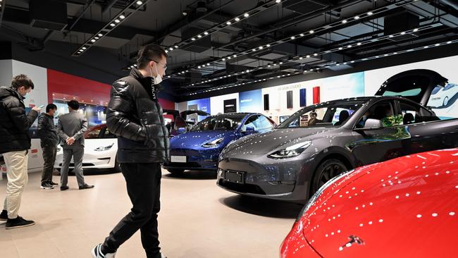 People look at a Tesla Model Y car at a Tesla showroom in Beijing on January 5, 2021. (Photo by WANG Zhao / AFP)