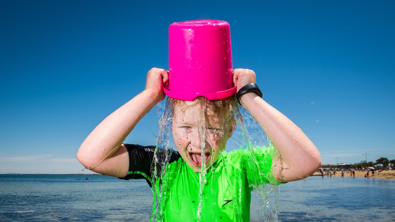 Harry, 7, cools off with a bucket of water at Williamstown. Picture: Jake Nowakowski