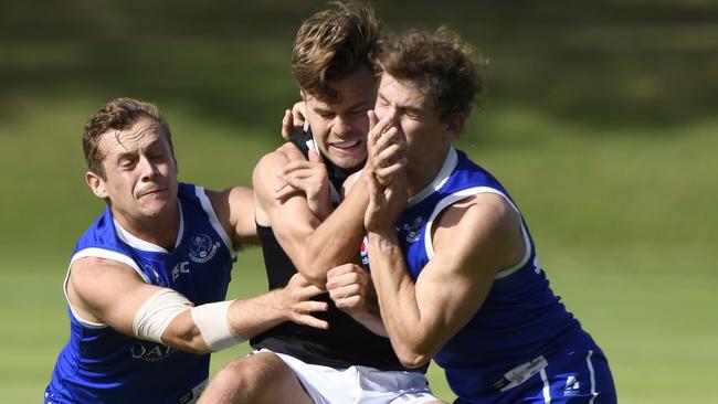 Adelaide Uni’s Matthew Langridge got a kick away before being crunched by two SPOC opponents. Picture: Naomi Jellicoe