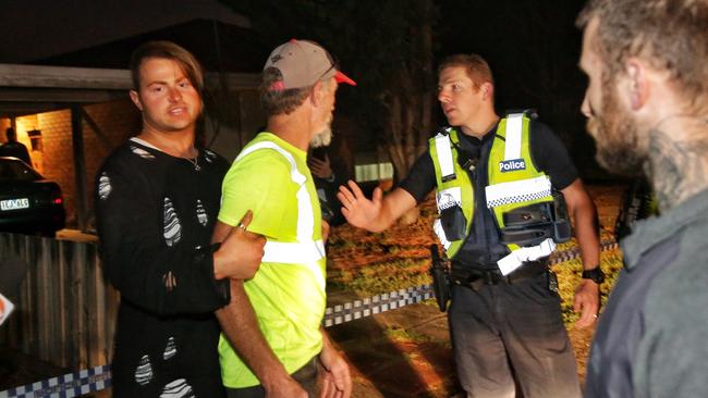 The victim's partner is restrained by his son during a confrontation with police. Picture: Hamish Blair