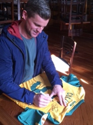 Jason Culina signing a Socceroo jerseys for Bailey Rogers.